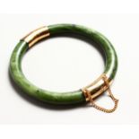 A CHINESE APPLE GREEN AND GOLD JADE BANGLE.