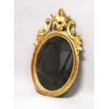 A 19TH CENTURY OVAL GILT FRAMED MIRROR, with carved cresting. 2ft 10.5ins high x 1ft 9ins wide.