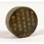 A SMALL CHINESE CIRCULAR BRONZE BOX, decorated with calligraphy. 3ins diameter.