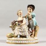 A 19TH CENTURY MEISSEN PORCELAIN GROUP OF A BOY AND GIRL, with goat and fruiting vines. Cross swords