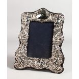 A CUPID AND SCROLL SILVER PHOTOGRAPH FRAME. 8ins x 7ins.