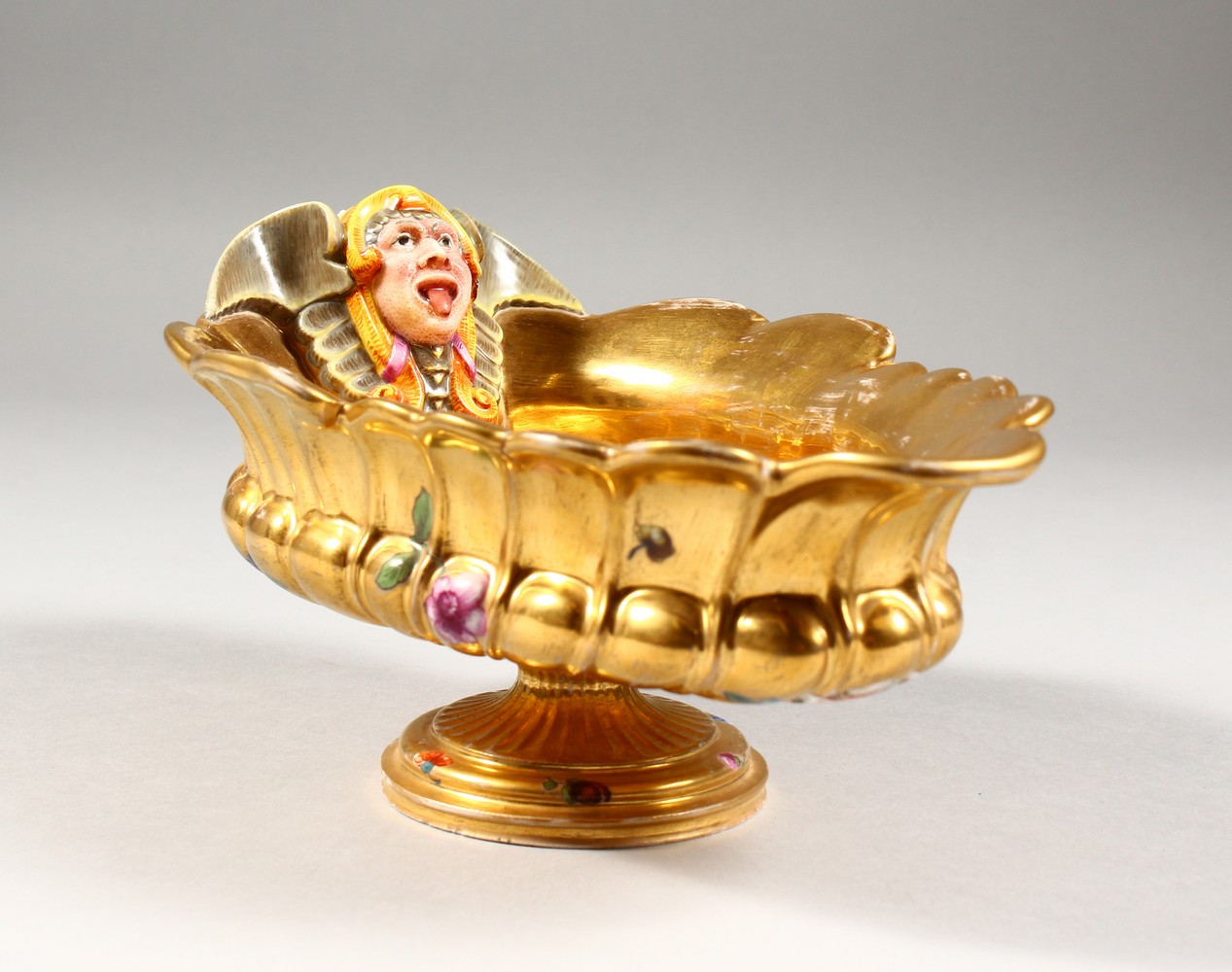 A BERLIN GILT PORCELAIN SAUCEBOAT, with grotesque mask, the centre painted with cupids. 8ins