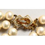 A TRIPLE ROW PEARL CHOKER with gold and diamond clasp.