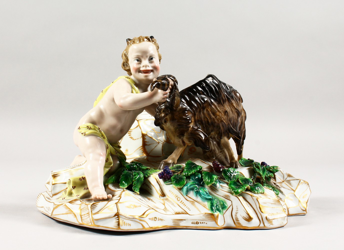 A GOOD MEISSEN PORCELAIN GROUP of a faun wrestling with a goat, on a gilt encrusted base. Incised