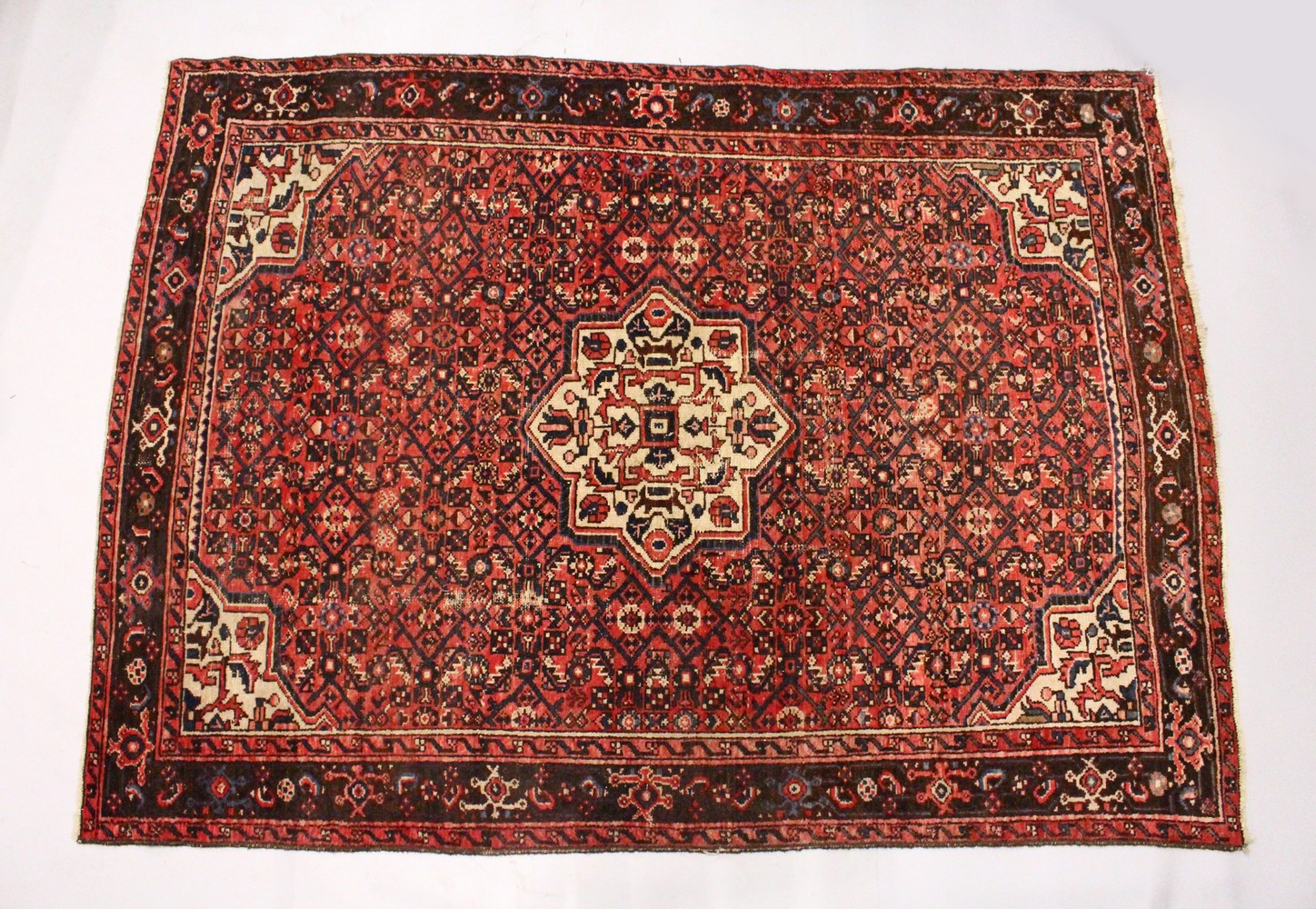 A PERSIAN RUG, 20TH CENTURY, red ground with central medallion, within a dark blue border. 6ft 10ins