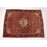 A PERSIAN RUG, 20TH CENTURY, red ground with central medallion, within a dark blue border. 6ft 10ins