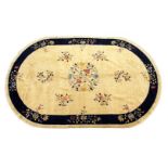 A GOOD CHINESE OVAL CARPET, beige ground with floral decoration, within a similar blue ground