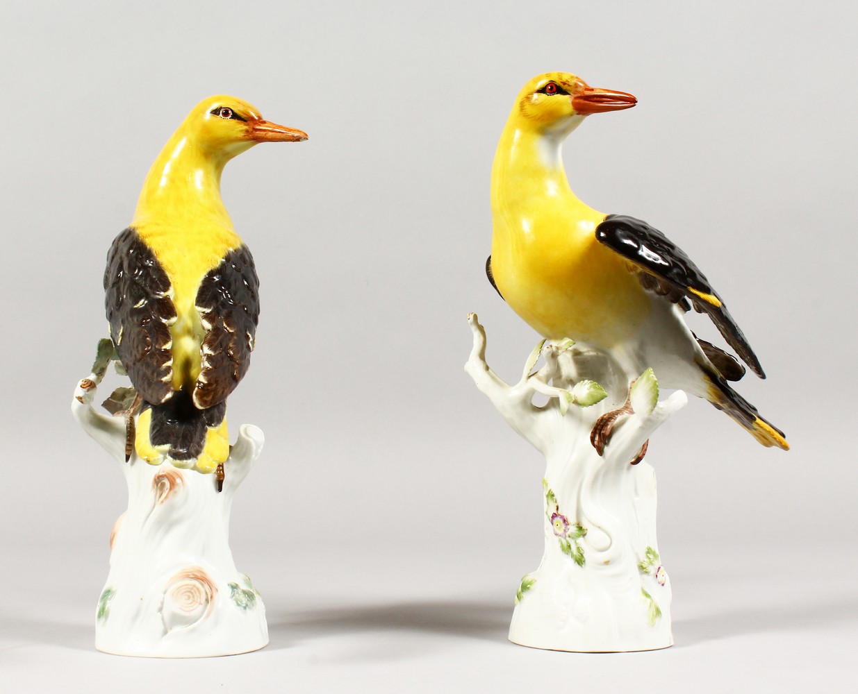 A VERY GOOD PAIR OF 19TH CENTURY MEISSEN BIRDS "GOLDEN ORIOLES" standing on encrusted tree stumps.