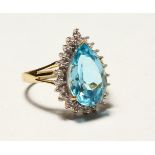 A 9CT GOLD BLUE TOPAZ TEARDROP RING.