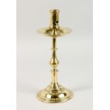 AN 18TH CENTURY CONTINENTAL BRASS CANDLESTICK, on a circular base. 11.5ins high.