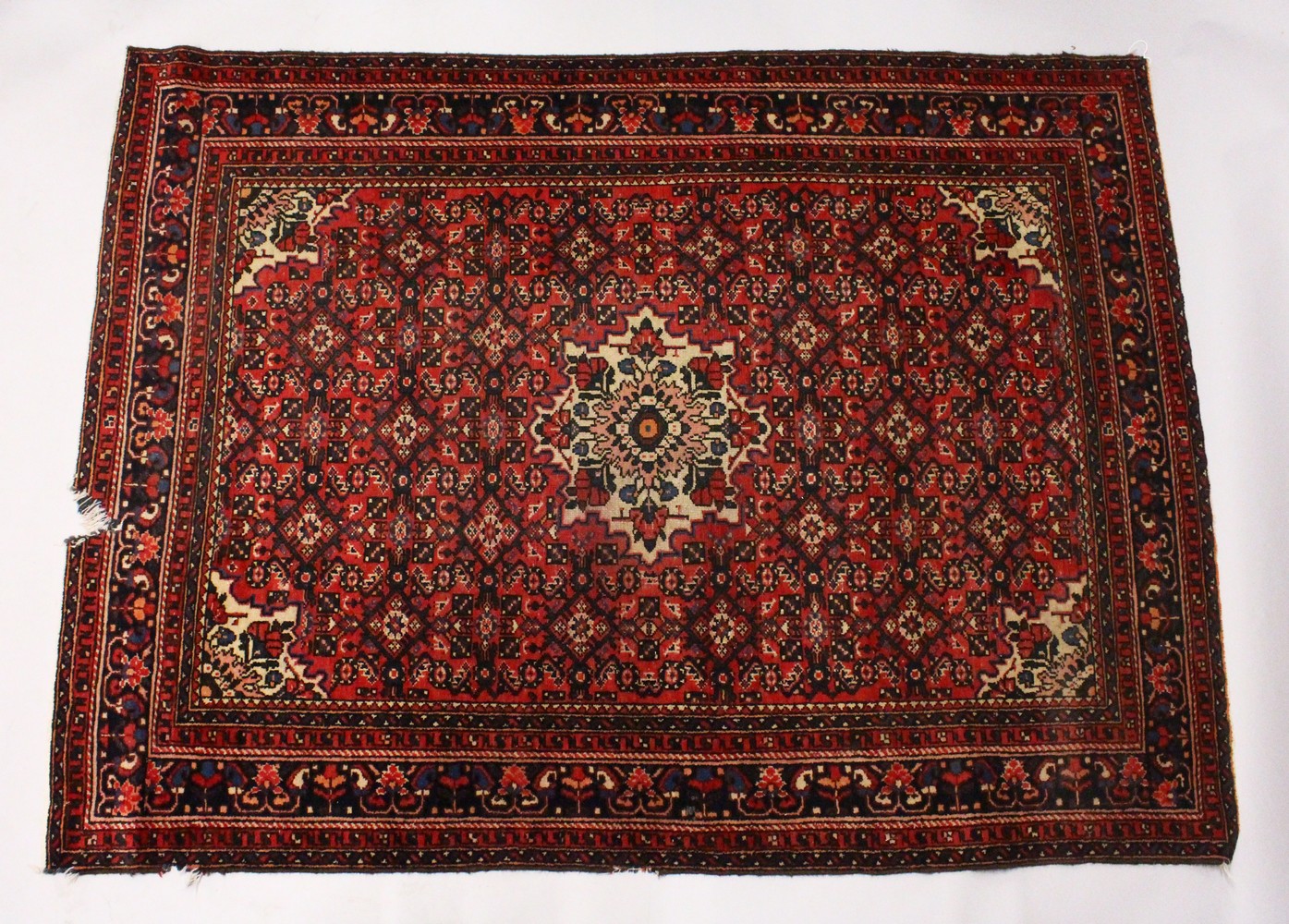 A PERSIAN RUG, 20TH CENTURY, red ground with central medallion, within a dark blue border. 6ft