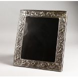 AN UPRIGHT SILVER PHOTOGRAPH FRAME decorated with fruiting vines. 12ins x 10.5ins.