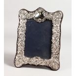 A SCROLL AND FLORAL SILVER PHOTOGRAPH FRAME. 8ins x 6ins.