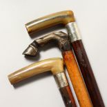 TWO WALKING STICKS WITH HORN HANDLED AND SILVER COLLARS; together with another stick, the horn