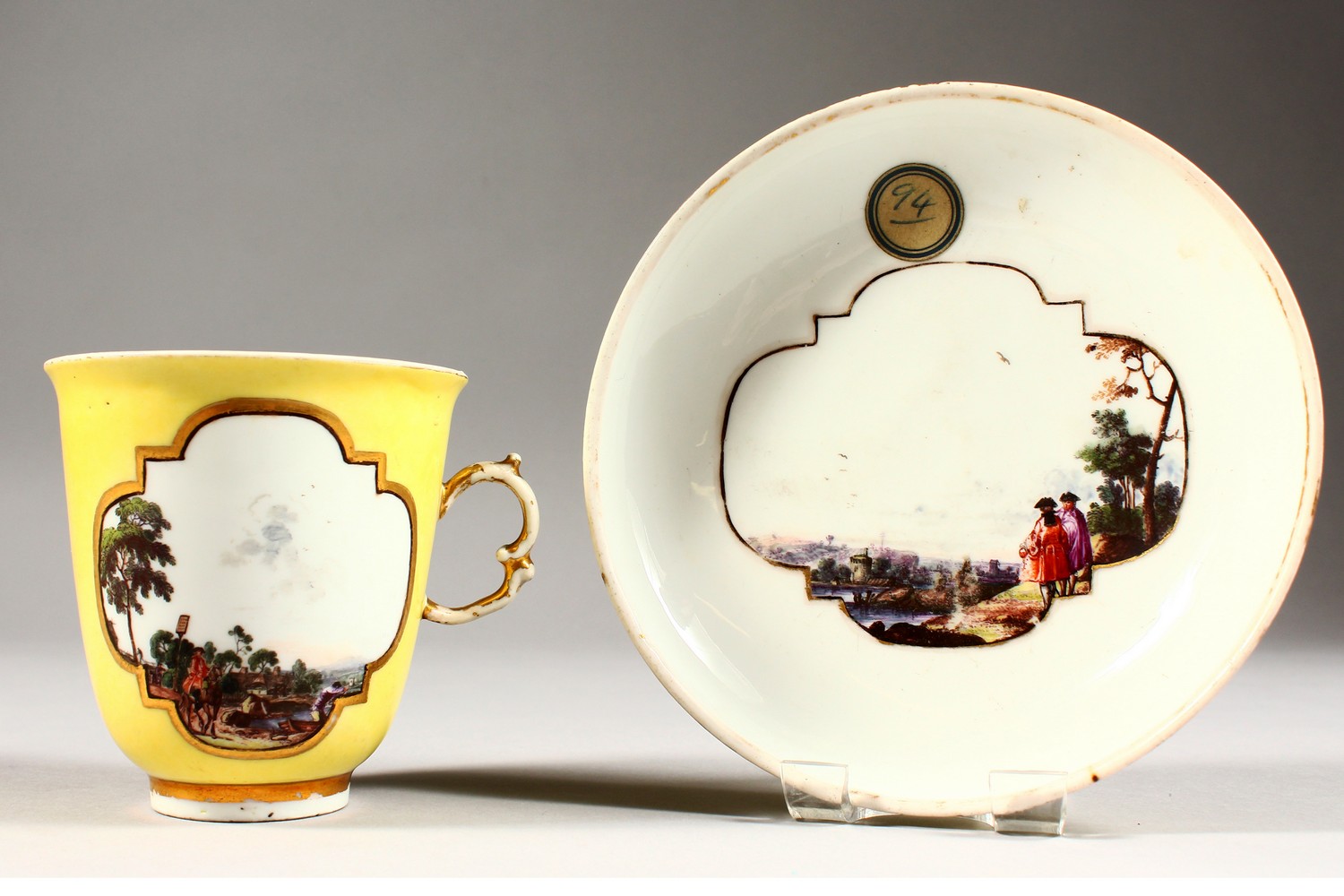 A SUPERB 18TH CENTURY MEISSEN CUP AND SAUCER, with yellow ground, the cup painted with two landscape