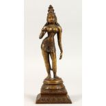 A 19TH / 20TH CENTURY INDIAN BRONZE FOGURE OF A DEITY / BUDDHA, in a stood pose 21.5cm high.