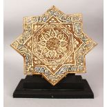 AN ISLAMIC EIGHT-POINTED STAR TILE with stand, the tile with calligraphy, 32cm x 32cm.