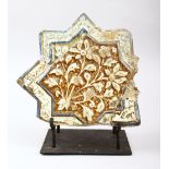 AN EARLY ISLAMIC KASHAN STAR TILE on a metal stand, with moulded floral decoration and