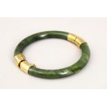 A GOOD 19TH CENTURY CHINESE CARVED JADE BANGLE, with gilt metal mounts, 5.5cm internal measurement.