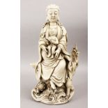 A LARGE CHINESE BLANC DE CHINE PORCELAIN FIGURE OF GUANYIN AND CHILD, seated upon a wooded outcrop