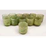 A GOOD SET OF TWELVE CHINESE CARVED GREEN JADE WINE CUPS, 6cm high x 5cm diameter.