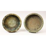 TWO 19TH CENTURY SELJUK INLAID BRONZE DISHES, with carved central roundels depicting mythical beasts