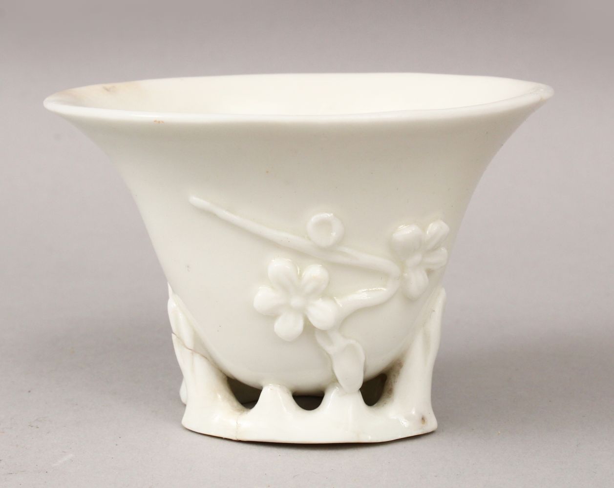 A 19TH CENTURY CHINESE BLANC DE CHINE PORCELAIN LIBATION CUP, with moulded relief decoration