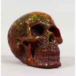 A CARVED COLOURED RESIN SKULL. 6ins long.