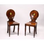 A GOOD PAIR OF REGENCY MAHOGANY HALL CHAIRS, the circular backs with painted crests, solid seats