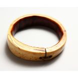 A GOOD IVORY TRIBAL BANGLE, 19TH CENTURY OR EARLIER, with old patination. 3.75ins diameter.