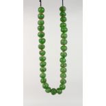 A STRING OF EARLY GREEN GLASS TRADE BEADS.