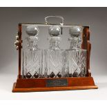 A GOOD THREE-BOTTLE CUT GLASS TANTALUS, with three whisky decanters & stoppers in a wooden frame.