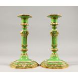 A PAIR OF APPLE GREEN PORCELAIN CANDLESTICKS with gilt decoration. 9ins high. One AF.