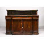 A REGENCY MAHOGAN BREAKFRONT SIDEBOARD, the gallery top with a brass rail, over a long frieze drawer