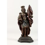 A 17TH/18TH CENTURY SMALL CARVED WOOD STANDING FIGURE, holding a flag, on a wooden base. 8ins high.
