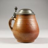 A BROWN POTTERY TANKARD, with pewter lid.