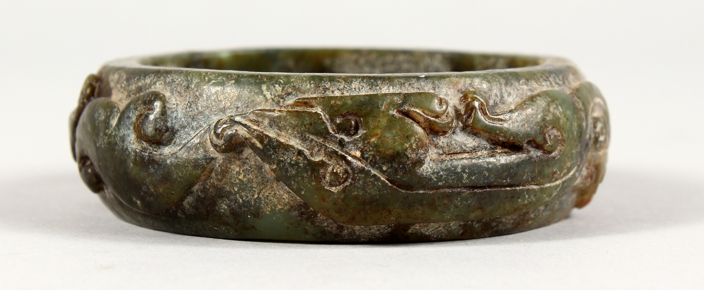 A GOOD LARGE CARVED DEEP GREEN JADE BANGLE.