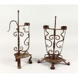 TWO 18TH/19TH CENTURY WROUGHT IRON CANDLESTICKS, on scrolling feet. 17.5ins and 19ins high.