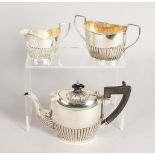 A SMALL SEMI FLUTED TEA SET, comprising teapot, sugar basin and milk jug. Birmingham 1898.