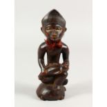 A SMALL AFRICAN CARVED WOOD FIGURE, seated man and child. 9ins high.