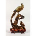 A CARVED HARDSTONE GROUP OF TWO BIRDS, on a wooden base.