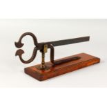 A 19TH CENTURY WROUGHT IRON SUGAR LOAF CUTTER, on wooden base. 14.5ins long.