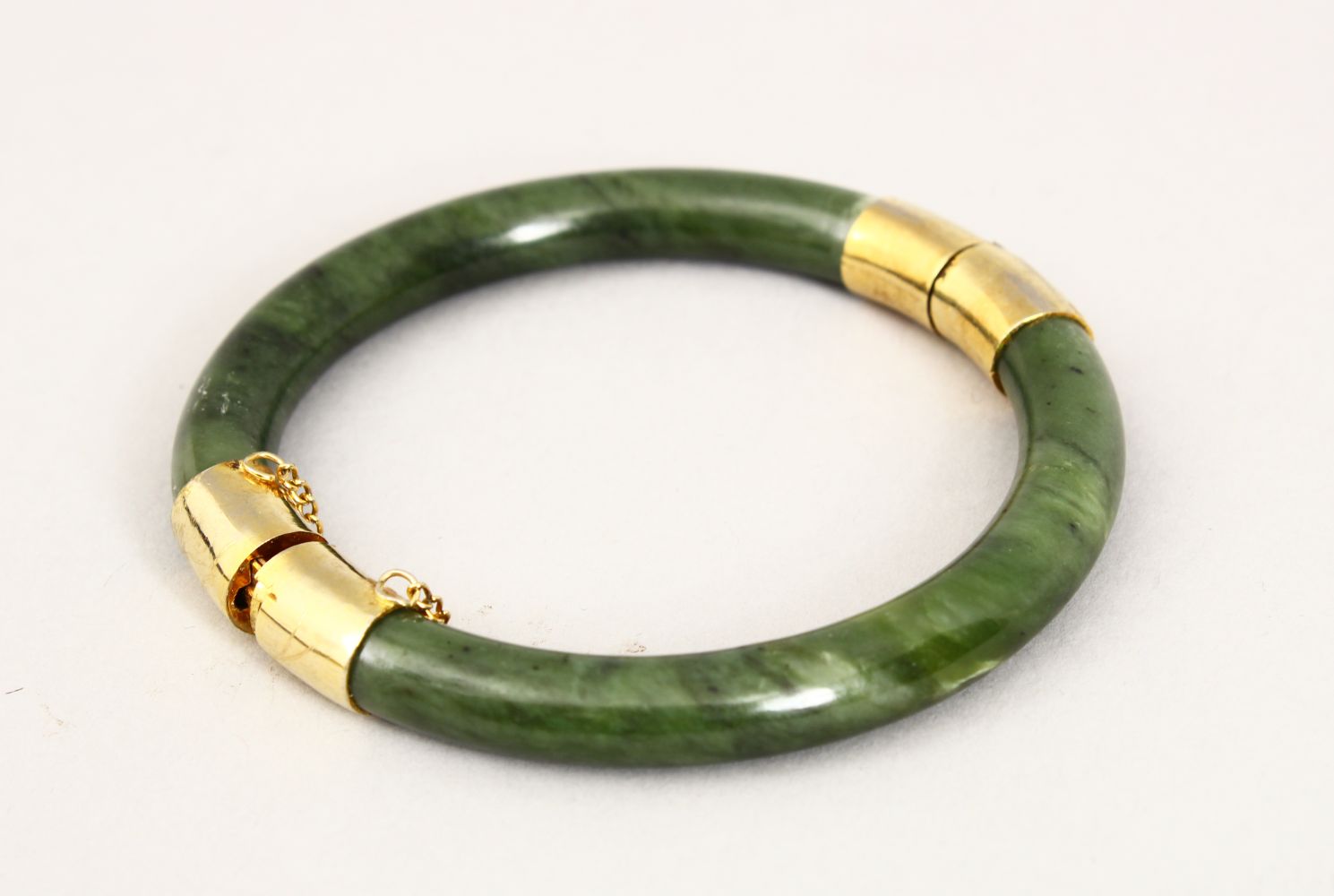 A GOOD 19TH CENTURY CHINESE CARVED JADE BANGLE, with gilt metal mounts, 5.5cm internal measurement.