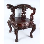 A GOOD 19TH CENTURY CHINESE CARVED HARD WOOD DRAGON CORNER ARM CHAIR, the arms of the chair carved