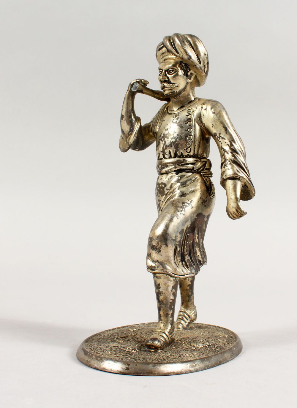 A GOOD INDIAN / ISLAMIC WHITE METAL FIGURE OF A MAN, the man upon a stylized shell base with an