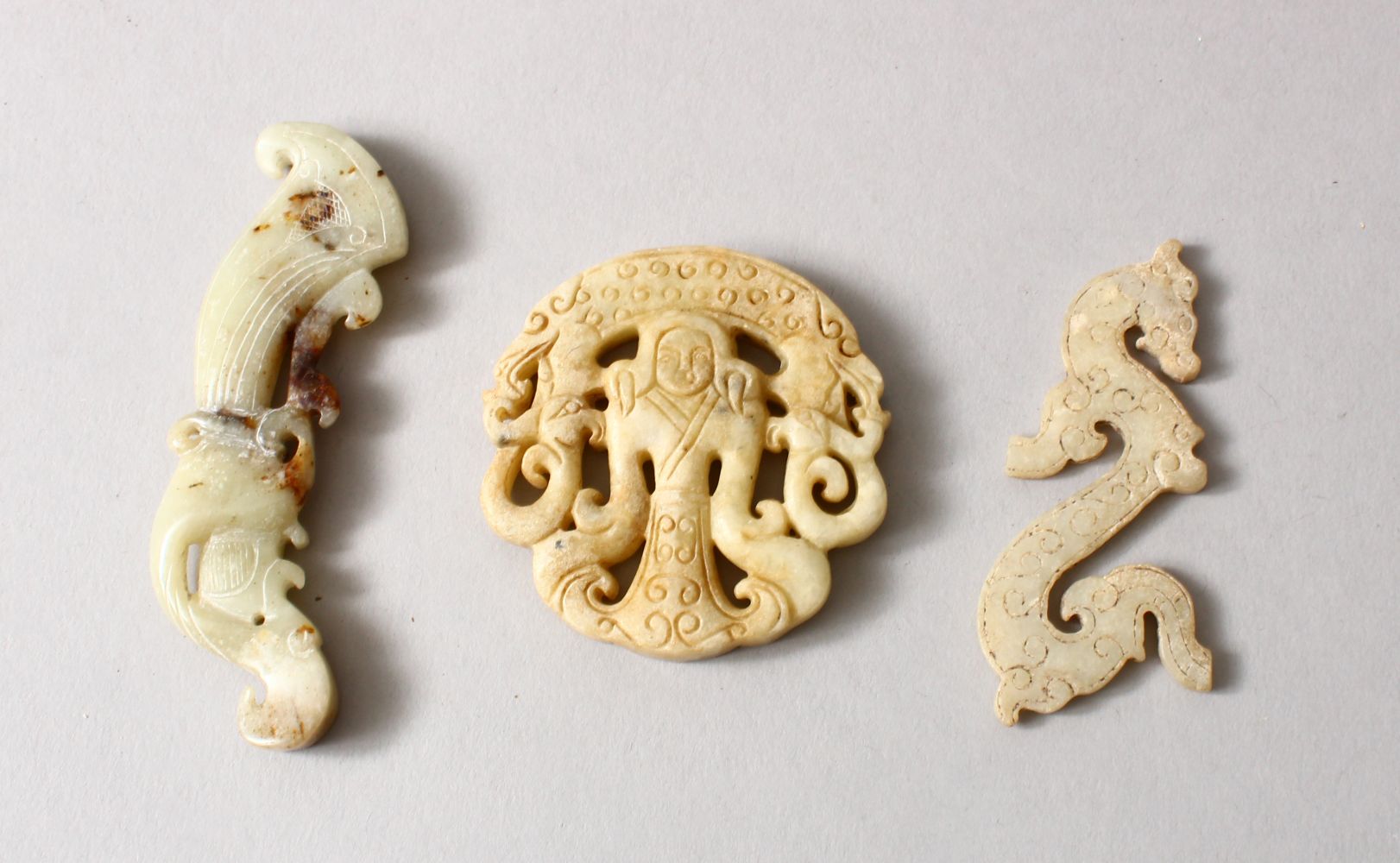 THREE CHINESE CARVED JADE / HARD STONE PENDANTS, two depicting figures, one in the form of a