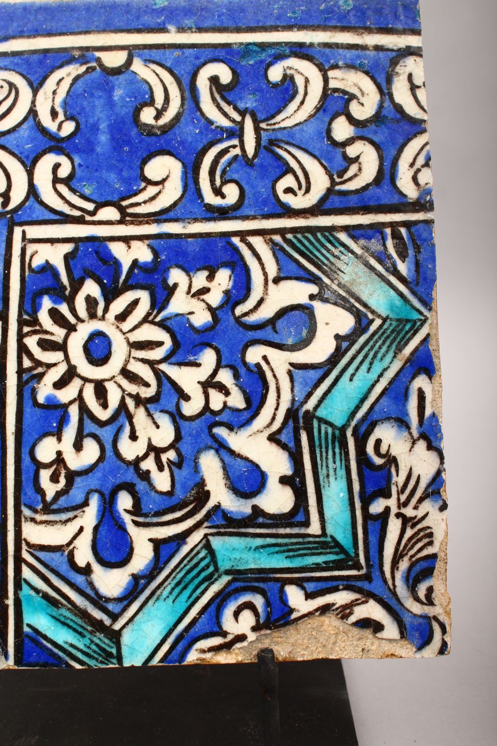 A 19TH CENTURY PERSIAN QAJAR BLUE AND WHITE CORNER TILE on a metal stand, tile 21.5cm x 21.5cm. - Image 5 of 11