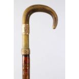 A GOOD 19TH CENTURY RHINO HORN HANDLE WALKING CANE, with a gilt metal collar, the stic with carved