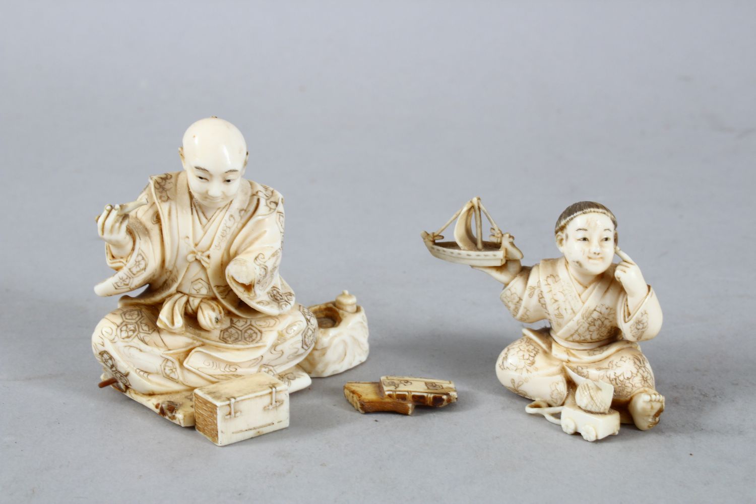 TWO JAPANESE MEIJI PERIOD CARVED IVORY OKIMONO, one carved to depict a seated artisan, the base with