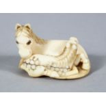 A GOOD JAPANESE MEIJI PERIOD CARVED IVORY NETSUKE OF A RECUMBENT HORSE, to horses in a recumbent